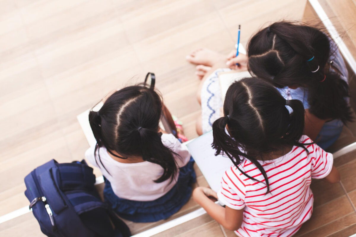 満開の桜並木の下、ランドセルを背負って元気に登校する新一年生の子供の後ろ姿。入学祝いのイメージ。