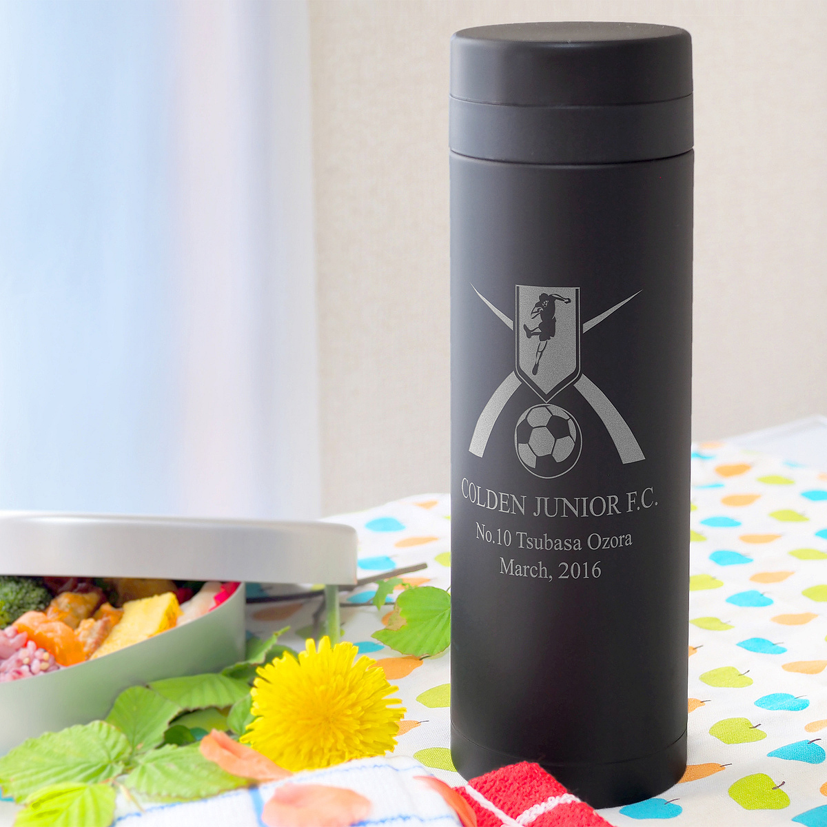 スタイリッシュなブラックのステンレス製マグボトル (500mL)。表面にはお名前とスポーツのモチーフが刻印されている。中学・高校の入学祝いに。