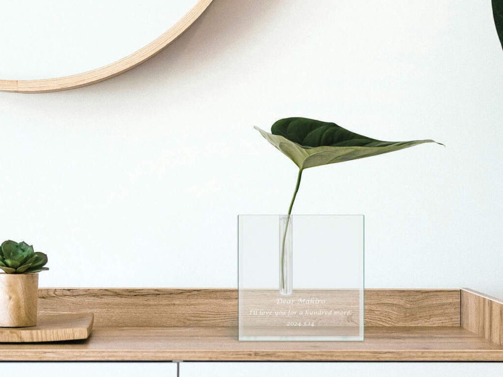 窓際で光を反射して輝くガラスの一輪挿し。お部屋の雰囲気を明るくする、名入れメッセージ入りのスタイリッシュなフラワーベース。