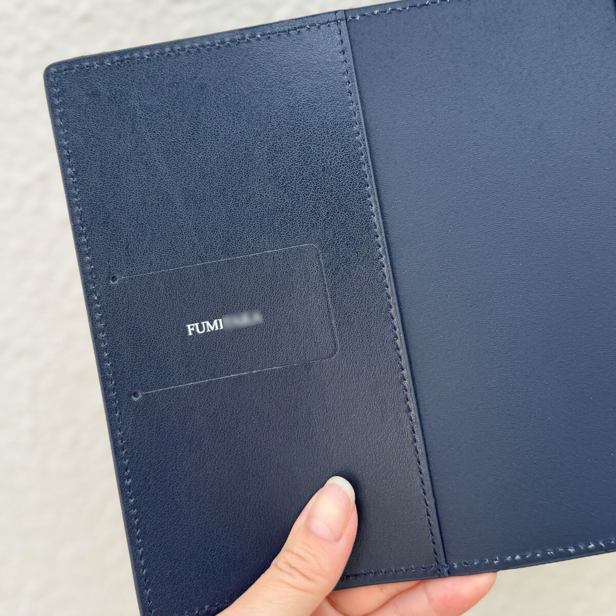 本革レザーブックカバーの表面に施された精密な名入れ刻印のアップ。職人の手仕事が光るオーダーメイドの証