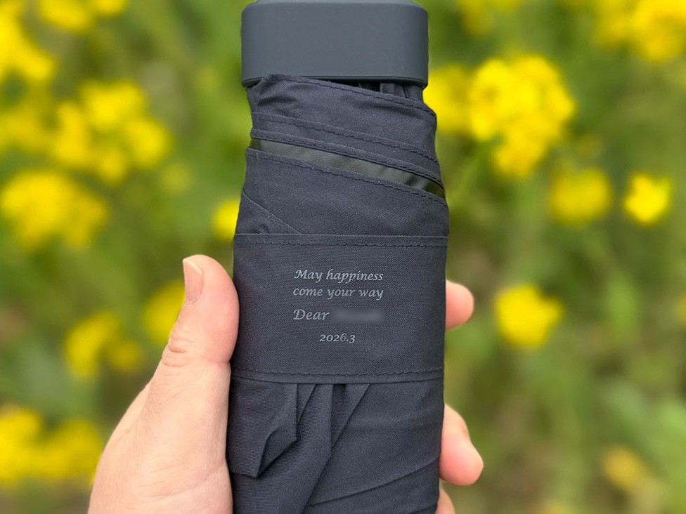 実際にオーダーいただいた、名前や日付が精密に刻印された傘のベルト部分。職人の手作業による一次ソースの証明写真。