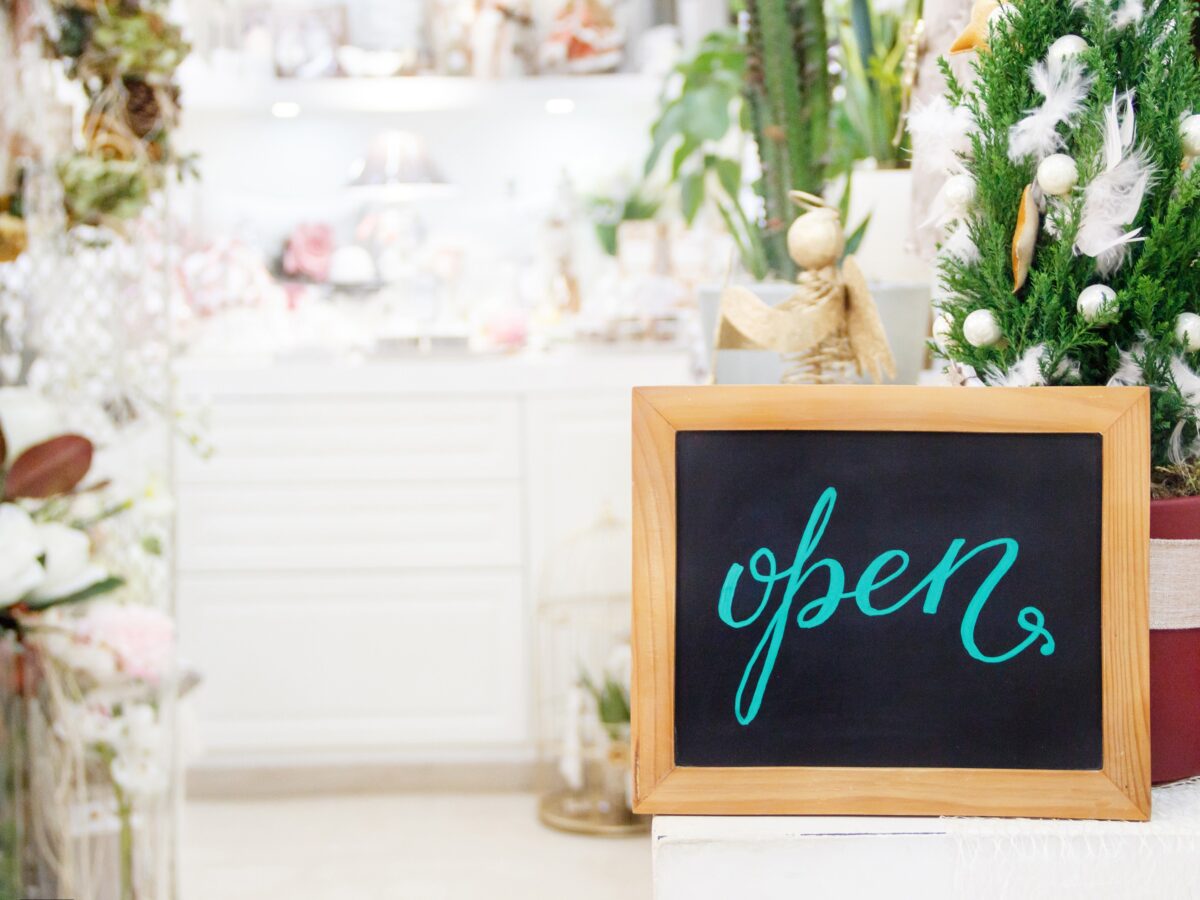 春の陽気に包まれたフラワーショップの店頭。黒板に『OPEN』の文字があり、新しいお店の始まりを予感させる風景