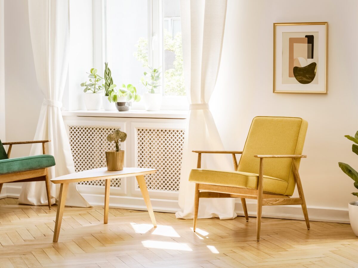 日差しが差し込む明るい窓辺に置かれたレトロなイエローのチェアとグリーンのソファ。新築祝いに喜ばれるおしゃれなインテリア空間のイメージ