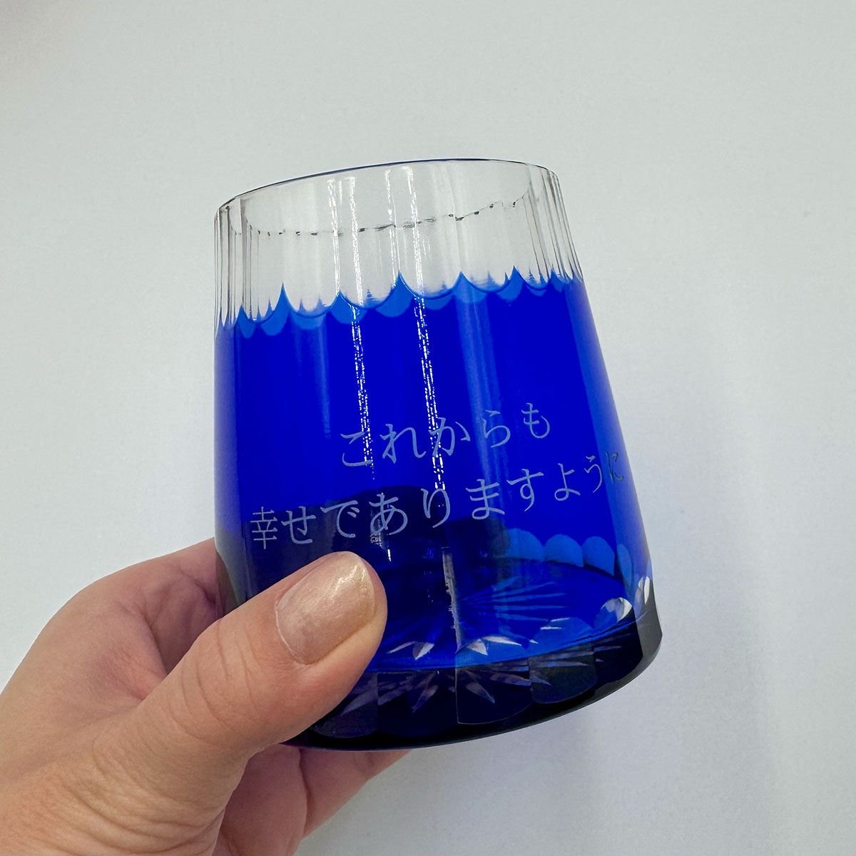 光にかざすことでお孫さんからの感謝メッセージの彫刻が美しく輝く、名入れ赤富士切子グラスの実物撮影（一次ソースの証明）