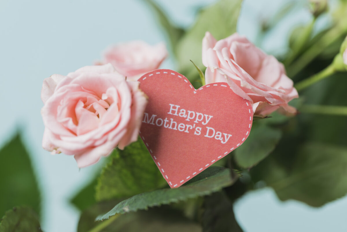 母の日をイメージした赤いペーパーハートとカーネーション。お母さんへの感謝を込めた名入れギフト選びを象徴するコンセプト写真。