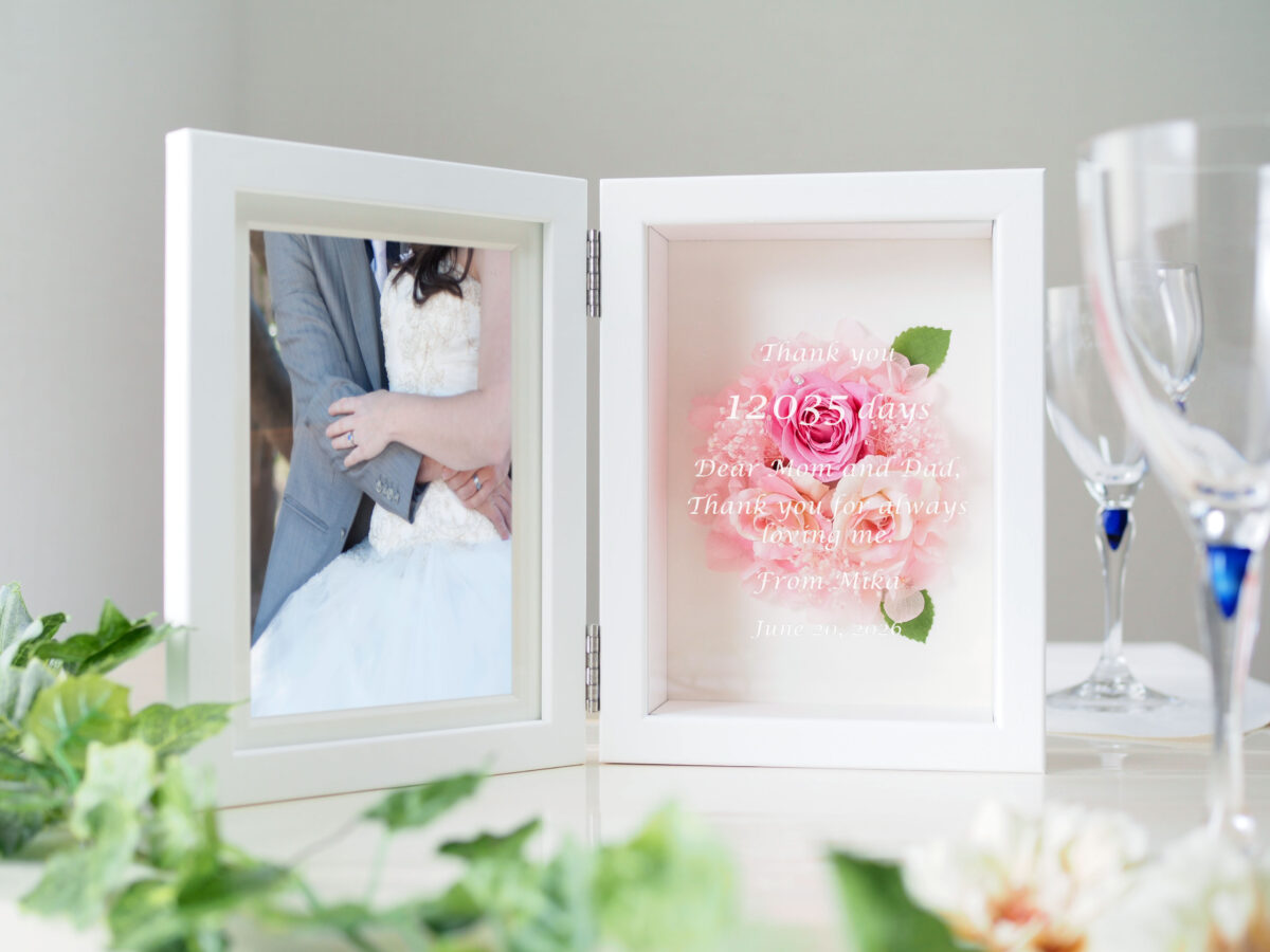 「Thank you 12035 days」など生まれてから結婚式までの日数が刻印された、ピンクのプリザーブドフラワー付きフォトフレーム。披露宴で両親へ贈る感動のオーダーメイド感謝状